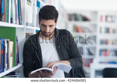 Portrait of happy student while reading book in school library. Study lessons for  exam. Hard worker and persistance concept.