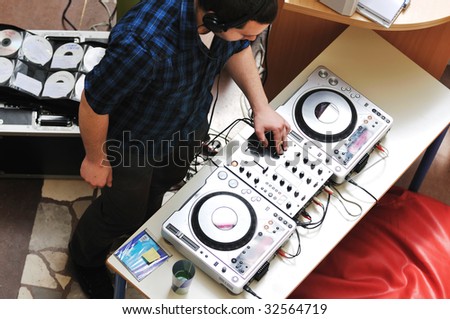 young dj man with headphones and compact disc dj equipment on party