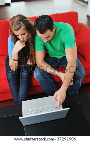 happy young couple have fun and relax at comfort bright apartment and work on laptop computer happy young couple have fun and relax at comfort bright apartment and work on laptop computer