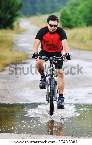young man drive mountain bike over water river