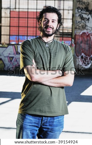 happy young man posing outdoor in urban environment with graffiti in background
