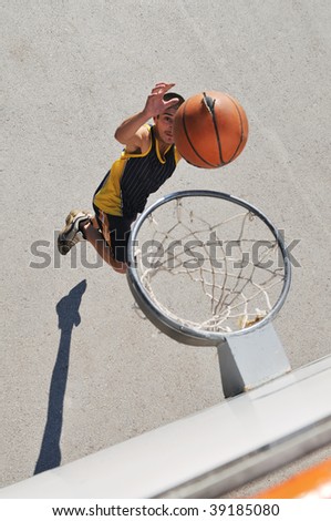 a young boy playing basketball outdoor on street with long shadows and bird view perspective
