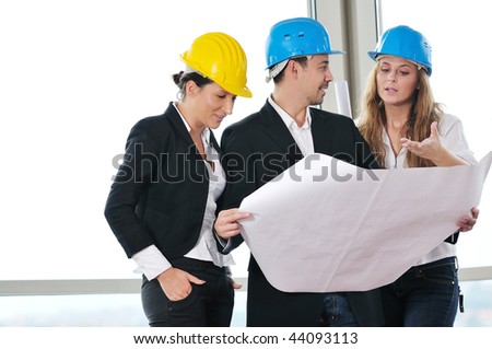 young architect group in big bright modern new apartment looking blueprints and building plans