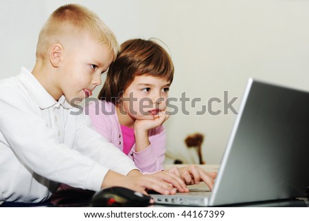 two happy children playing games and learning education lessons on laptop computer at home