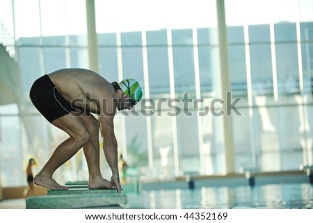 start position race concept with fit swimmer on swimming pool