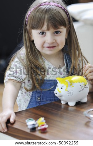 happy young girl  portrait at home while painting piggy bank and representing banking and finance concept