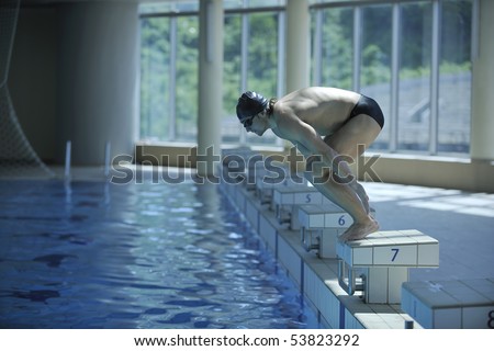 young swimmer on swim start at swimming pool ready for jump race and win