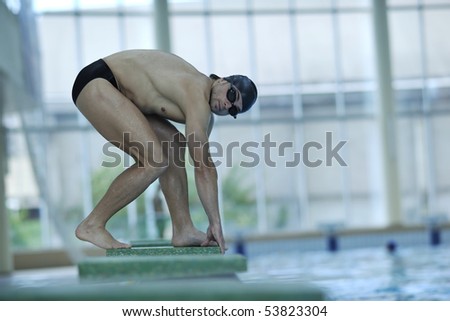 young swimmer on swim start at swimming pool ready for jump race and win