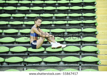 happy young woman streching at athletics stadium and relax
