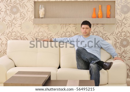 one happy young man relax at home in livingroom with modern style furniture indoor