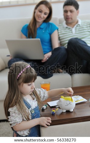young parrent at home with beautiful child make savings and put coins money in piggy bank