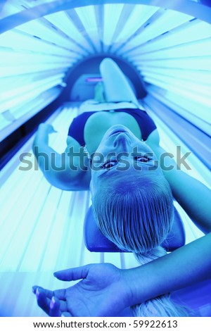 young woman at laying on solarium bed and get brown skin tone ready for summer