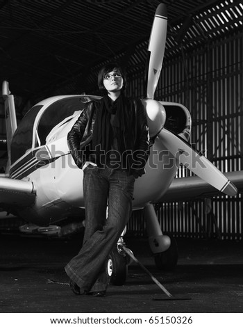 beautiful young woman model in fashion clothes posing in front of old private airplane