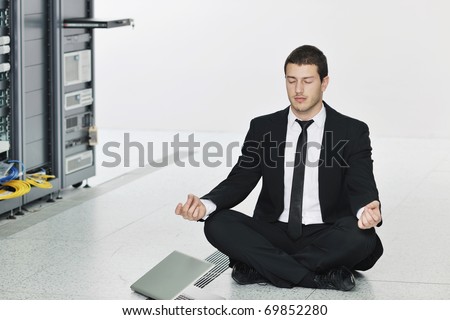 young handsome business man in black suit practice yoga and relax at network server room while representing stress control concept