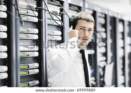 young business man computer science engineer talking by cellphone at network data center server room asking  for help and fast solutions and services