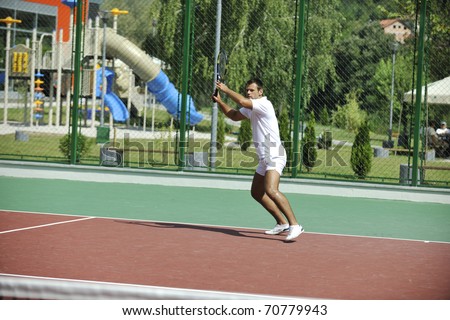 young man play tennis outdoor on orange tennis court at early morning