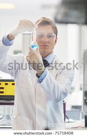 young doctor scientist in bright labaratory work research and  analyse content of  test tubes representing chemistry and research concept