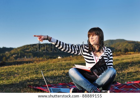 young teen girl read book and study homework outdoor in nature with blue sky in background
