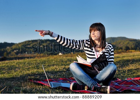 young teen girl read book and study homework outdoor in nature with blue sky in background