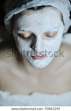 Young beautiful woman receiving cosmetic facial mask in spa beauty salon and relax