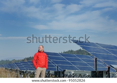 Male engineer at work place, solar panels plant industry in background