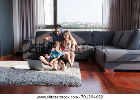 Happy Young Family Playing Together with laptop computer at home sitting on the sofa