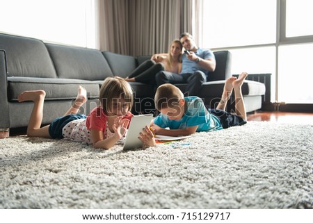 Happy Young Family Playing Together at home on the floor using a tablet and a children\'s drawing set