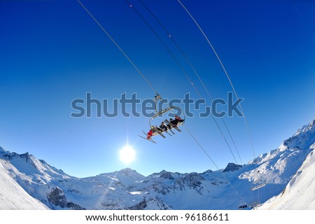 Ski lift - happy skiers use vertical transport  on ski vacation at sunny winter snow day