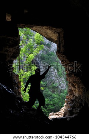 Silhouette of a man standing in front of a cave entrance