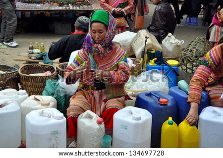 BAC HA - FEB 23: An unidentified old Black H\'mong woman selling rice wine in Bac Ha market. The H\'mong people are one of the largest ethnic minorities in Vietnam.  On Feb. 23, 2013 in Bac Ha, Vietnam