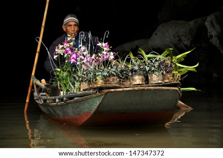 NINH BINH - FEB 21: Unidentified merchant selling orchids near a cave entrance. The Tam Coc cave is one of the most popular tourist destinations of Vietnam. On February 21, 2013 in Ninh Binh, Vietnam