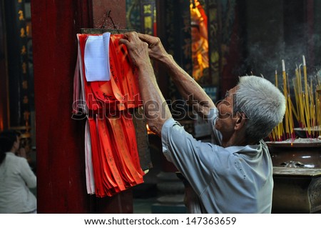 SAIGON - FEB 15: Old man hanging a wish letter in lunar new year in Chua Ba Thien Hau temple. On February 15, 2013 in Saigon, Vietnam. This is a tradition of Vietnamese people in lunar new year.