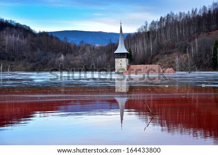 A flooded church in a toxic red lake. Water polluting by a copper mine