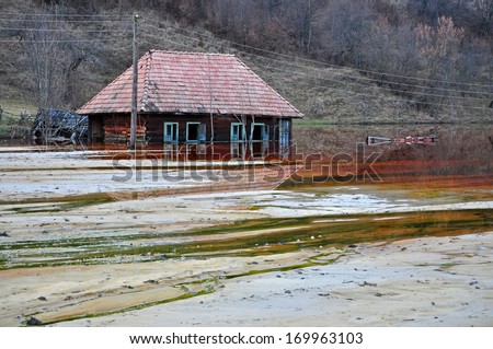 Ecological disaster. An abandoned village flooded by polluted water from a copper open pit mine