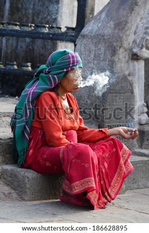 KATHMANDU, NEPAL - SEPTEMBER 29: Old, mature woman smoking medicinal herbs for relaxation on the streets of Kathmandu. On Sept. 29, 2013 in Kathmandu, Nepal
