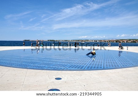 ZADAR - AUG 25: People walking on Greeting to the Sun sculpture. It consists of 300 multilayer glass panels and uses solar power to create a light show at night. On Aug 25, 2014 in Zadar, Croatia
