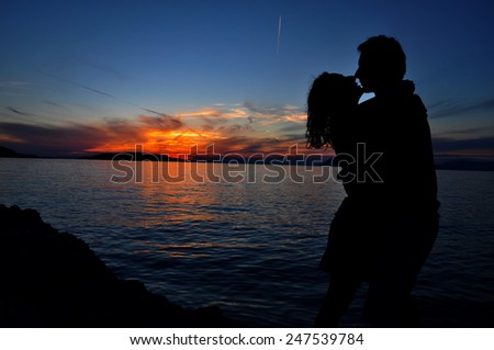 Romantic couple silhouette over sea sunset background