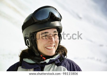 Portrait of a smiling skier woman with helmet in the Alps