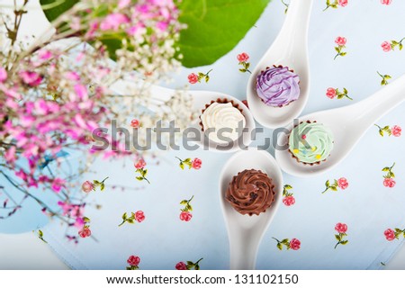 four candy on special spoon with a napkin on the table, next to a bouquet of flowers
