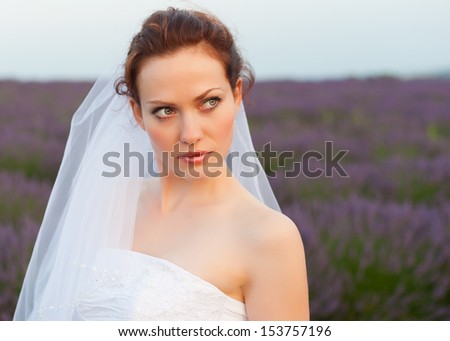 Young white girl with red hair in the form of a bride in a veil at lavender field