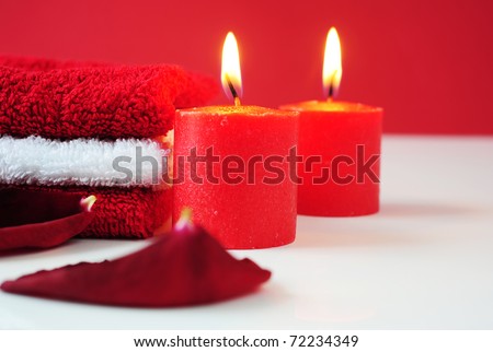 A tower of white and red towels, rose petals and lit red candles