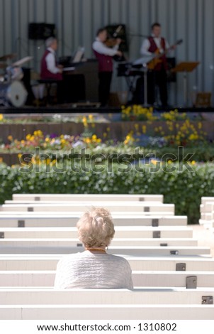 A lone elderly woman watching a jazz band in the Kurpark, Bad Homburg - Germany. Selective focus on lady.
