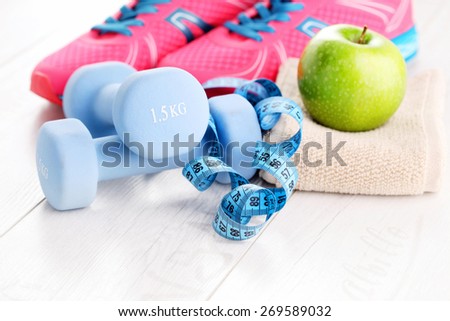 fitness concept with dumbbells and green apple - sport and leisure