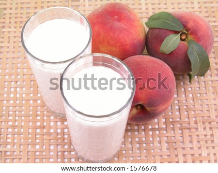 two glasses of peach smoothie and some fresh peaches