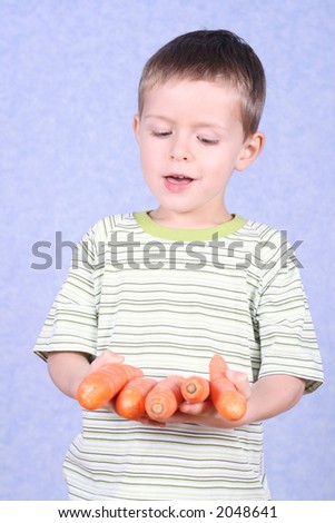 five years old boy holding fresh carrots