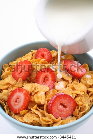 bowl of corn flakes with strawberry and jug of milk isolated on white
