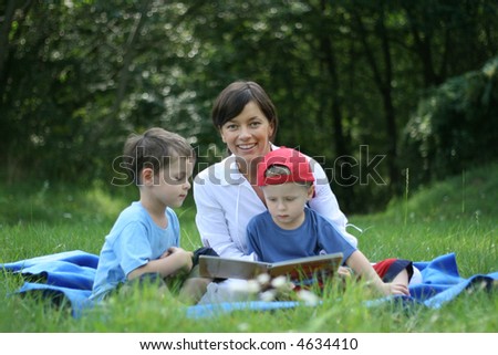 mother and two sons reading book outside