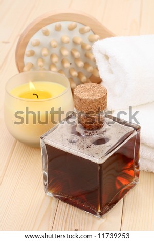 bottle of massage oil with brush and towels