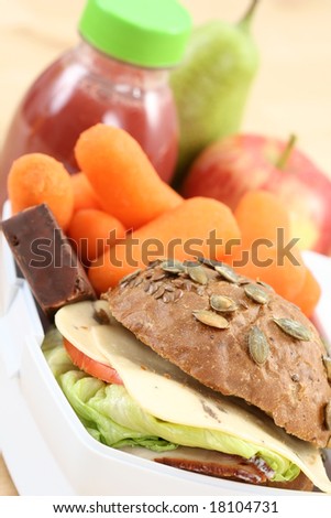 box with sandwich fruits and chocolate and bottle of juice