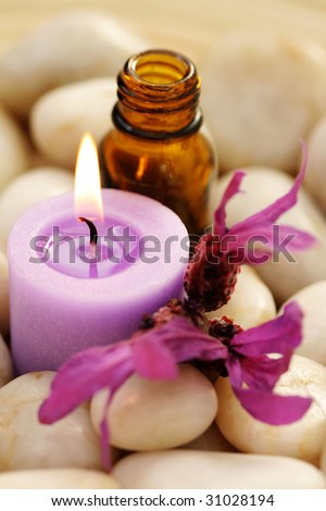 massage oil candle and lavender flowers in stones - relaxing time
